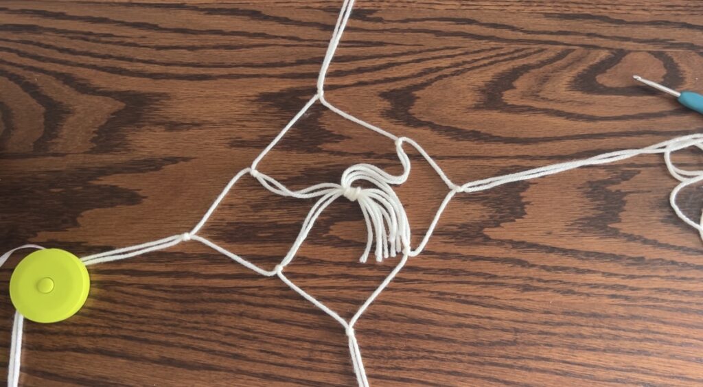 Demonstration of tying 8 knots of white yarn together on a wooden surface