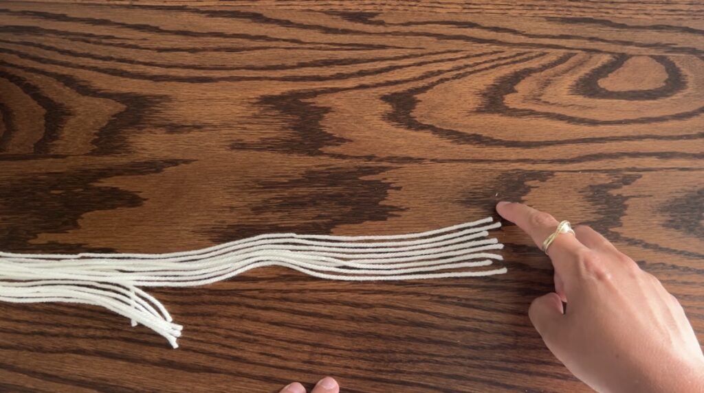 8 White strings of yarn laying on wooden surface