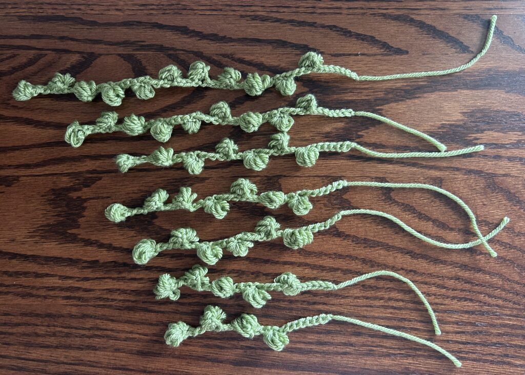 Green crochet strings with bulbs on them laying on wooden surface