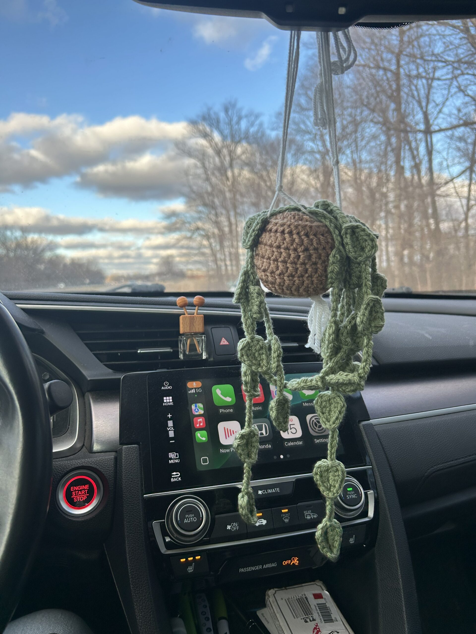 Crochet plant with vines in brown pot hanging from rearview mirror in car