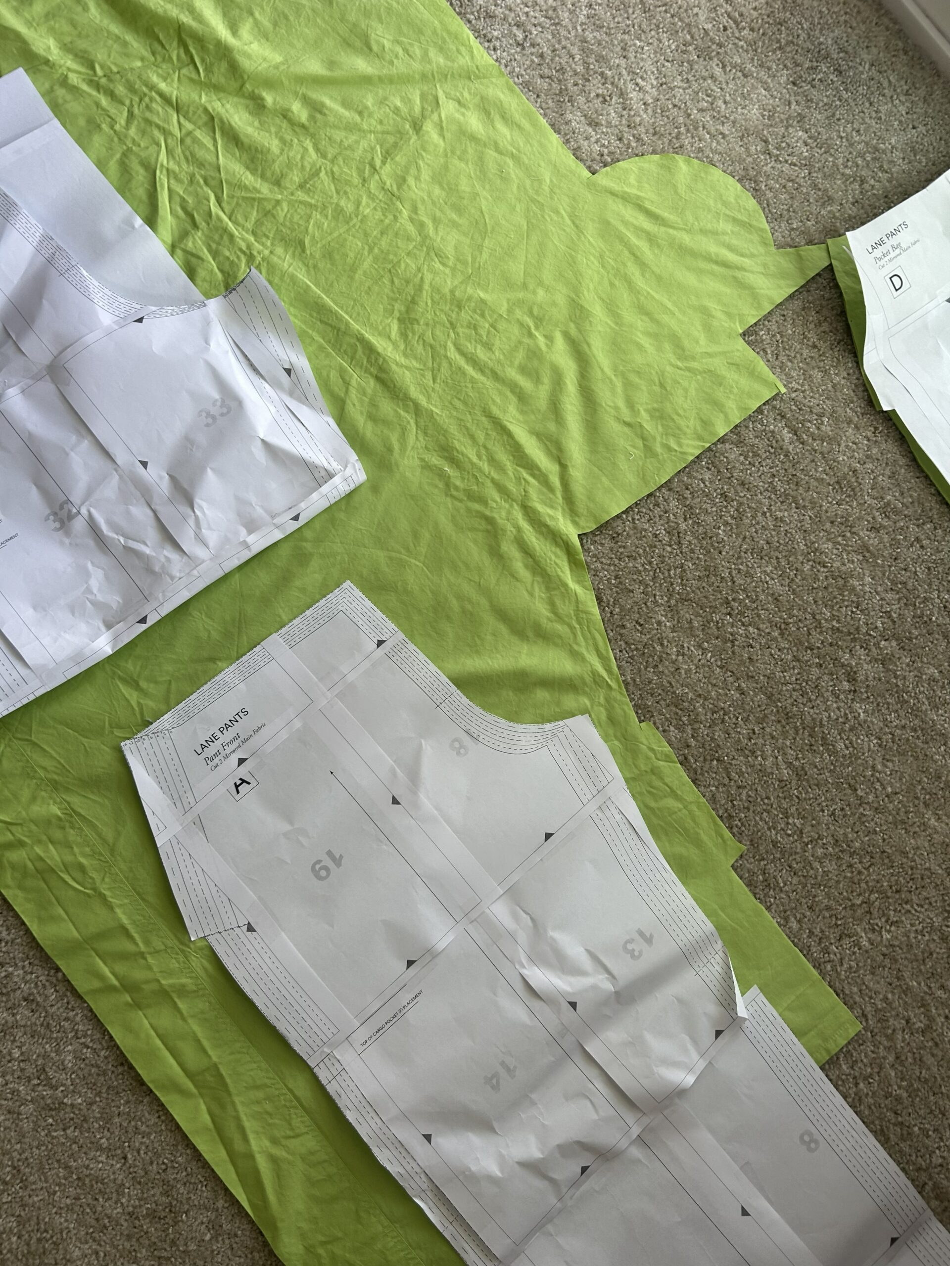 Lime green fabric and pattern pieces laying on carpeted floor