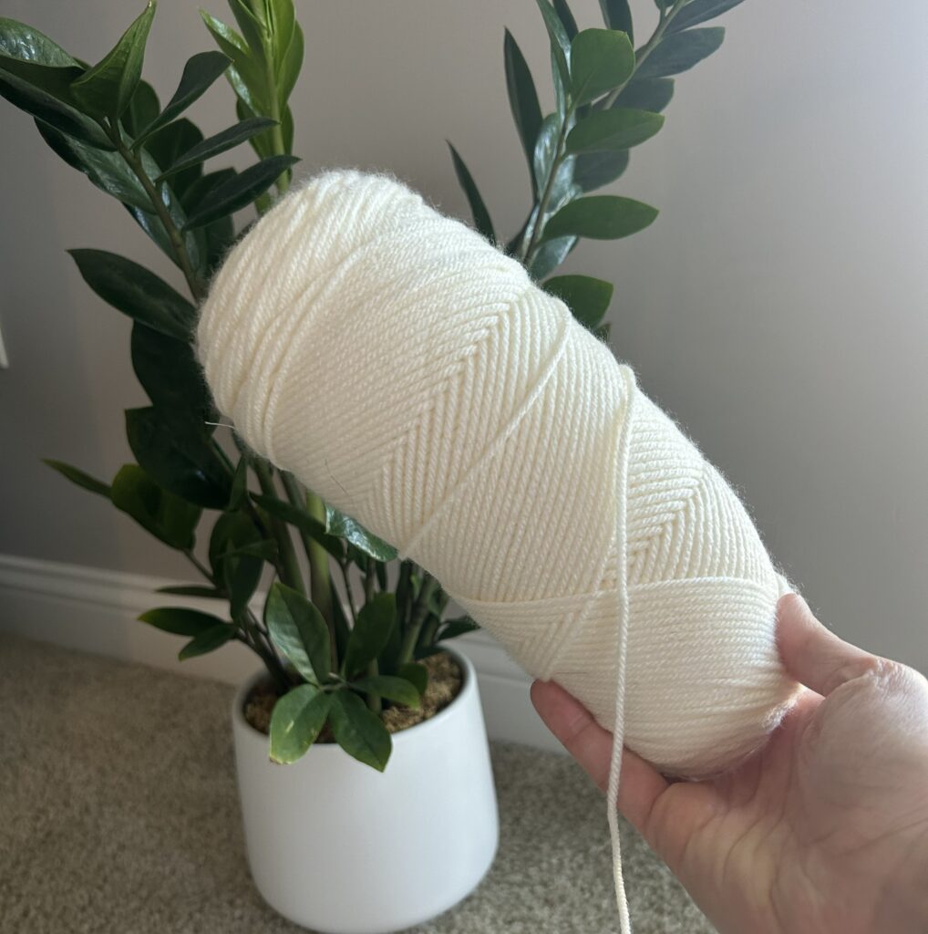Hand holding a white yarn skein