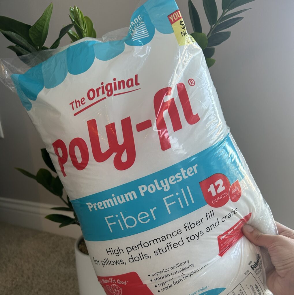 Hand holding a bag of white polyfil stuffing
