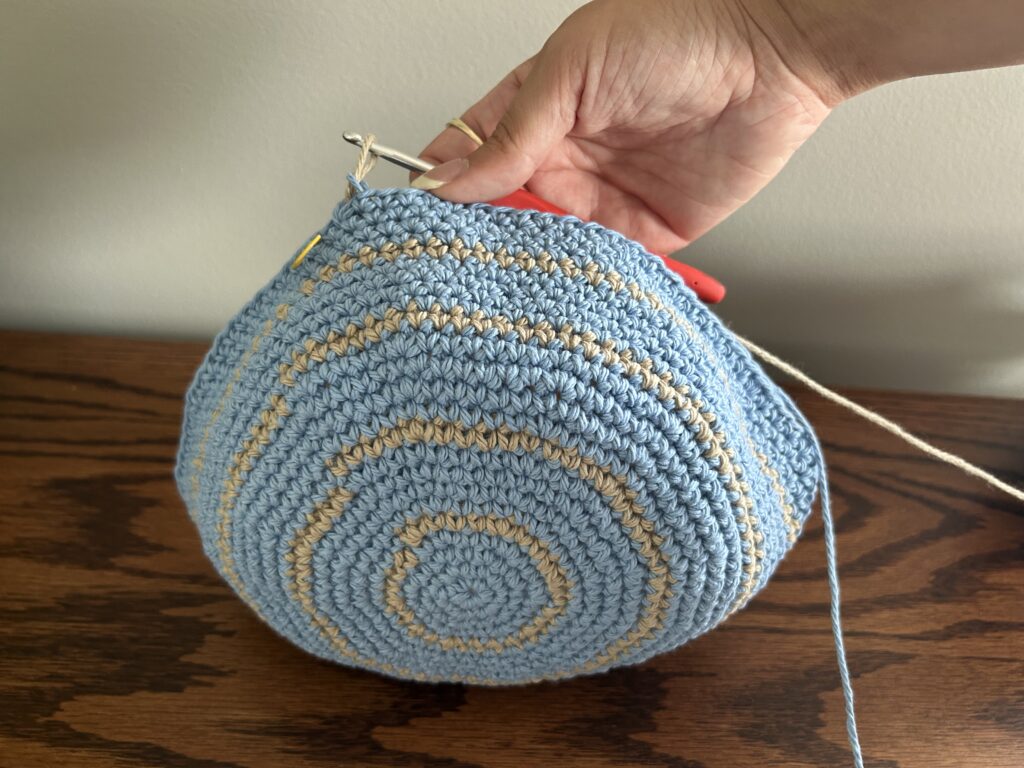 Blue and tan cotton yarn crochet bucket hat after round 24 of stripes