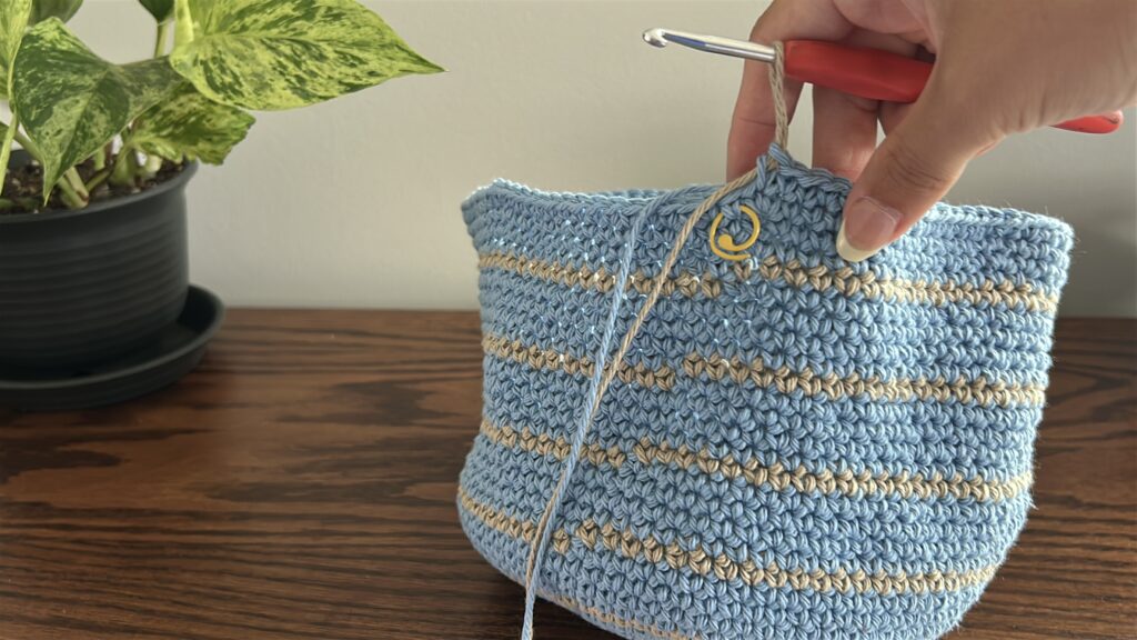 Blue cotton yarn working increases into crochet bucket hat to create the brim