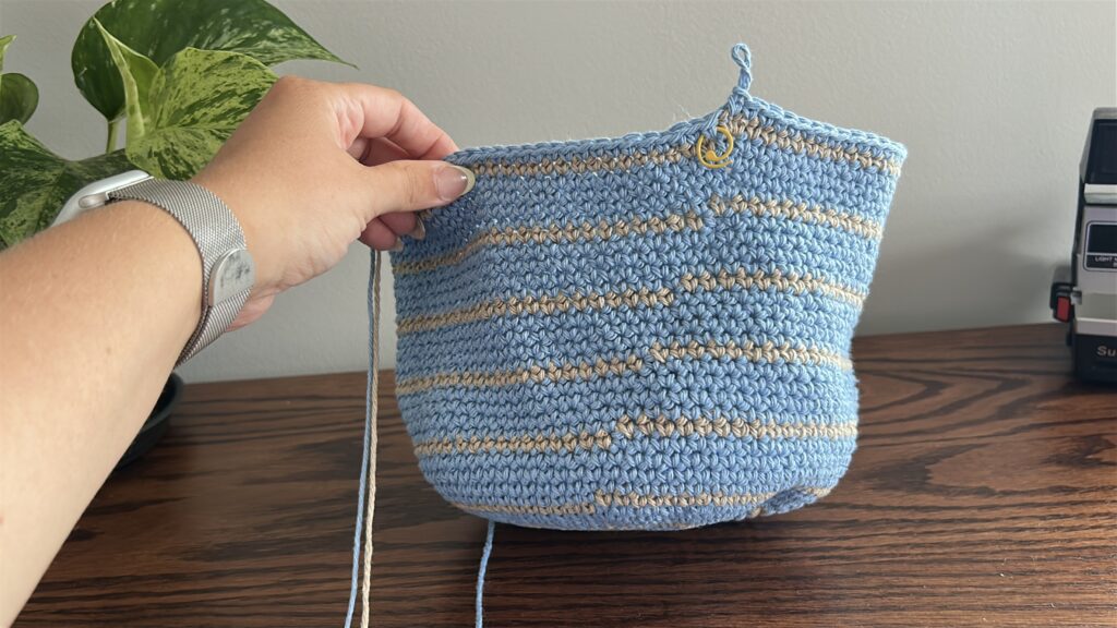 Round 41 of a Crochet Bucket Hat showing a blue and brown crochet magic ring and red crochet hook on dark wooden surface